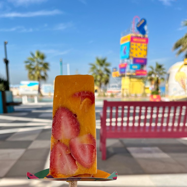 A popsicle of frozen mango pulp studded with strawberry slices.
